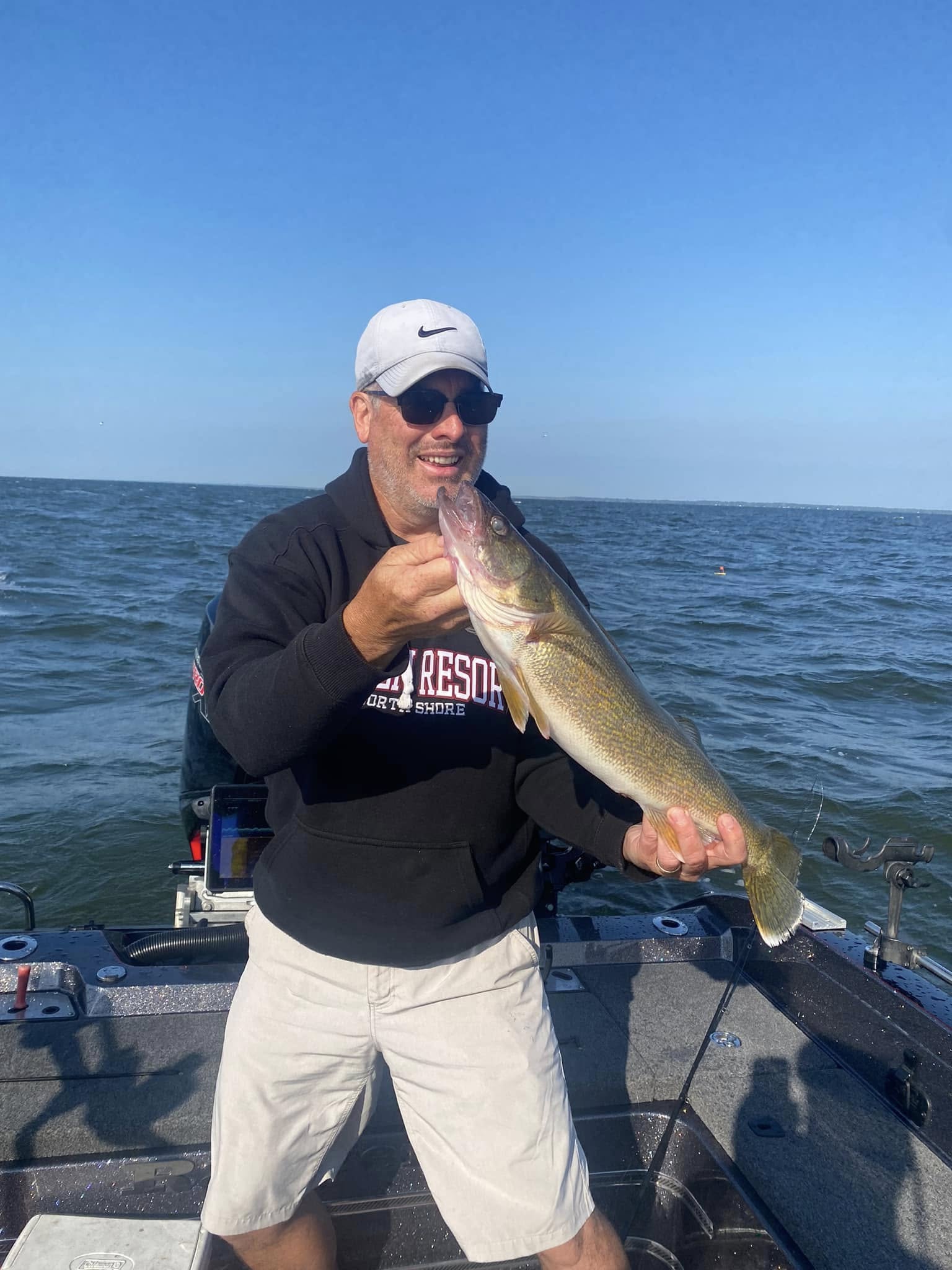 Client holding a walleye on open water during a guided trip