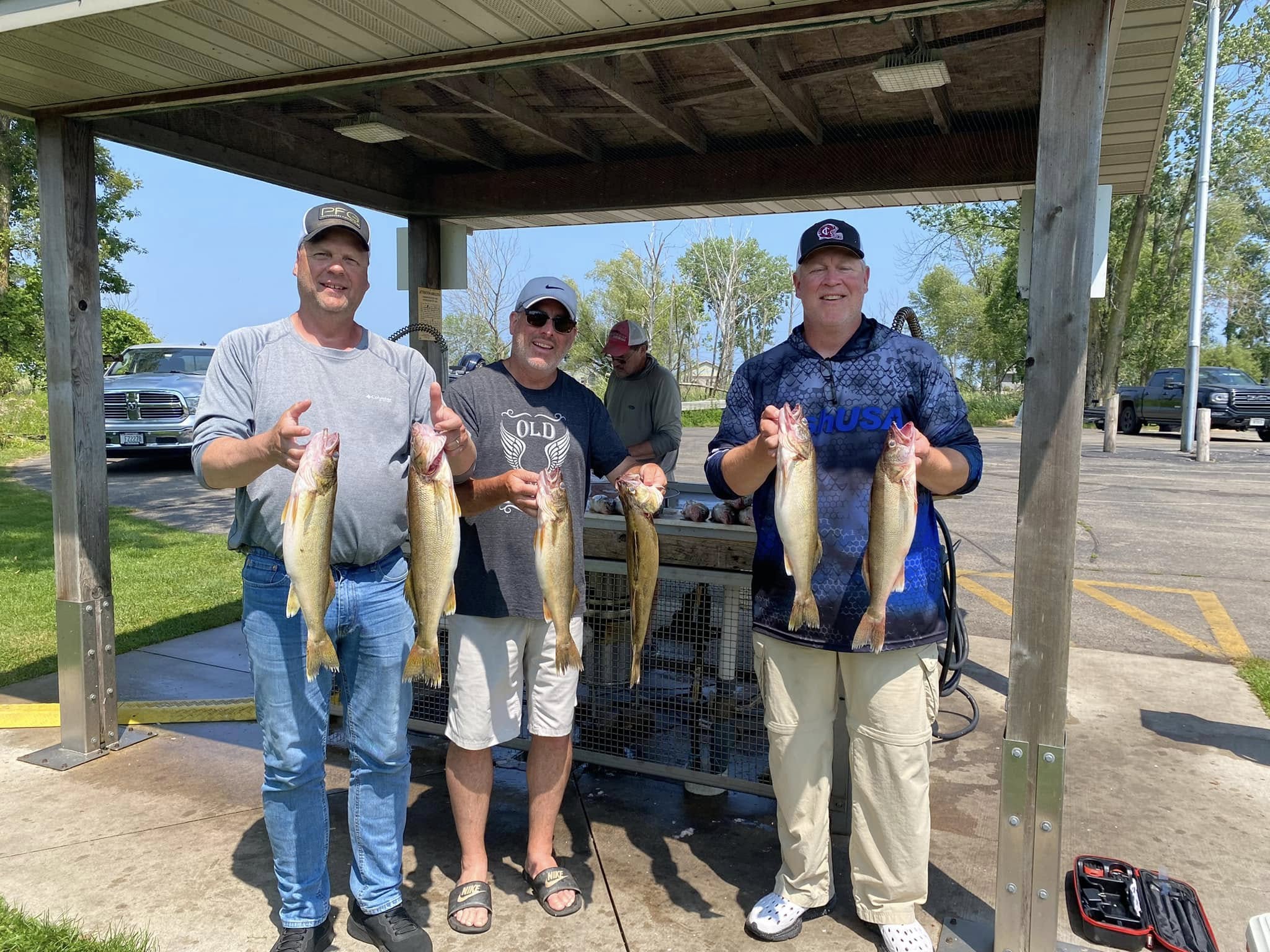 Three clients with a full limit of walleye at the fish cleaning station