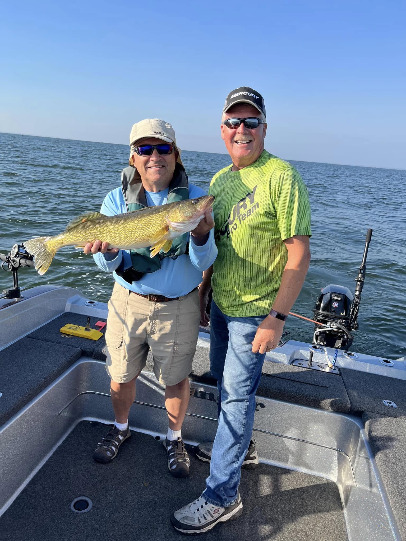 Wayne and client holding a walleye together on the boat